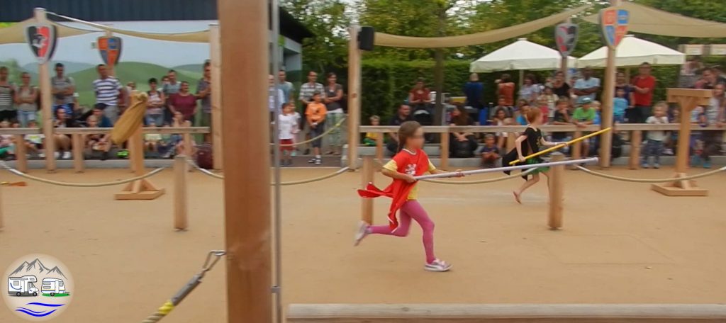 Kinder rennen mit einer Ritterlanze bei einer Vorführung vor Zuschauern in der Burgarena